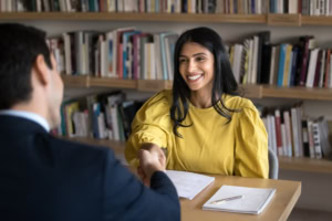 Cheerful Indian student woman talking to male professor in college